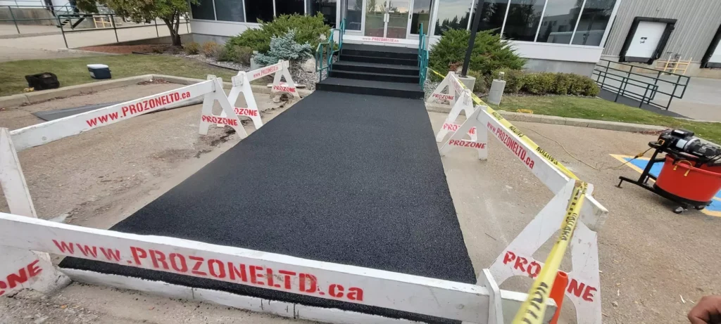 Newly installed rubber paving walkway secured with safety barriers in front of a commercial building, part of paving, asphalt repair, and concrete construction improvements