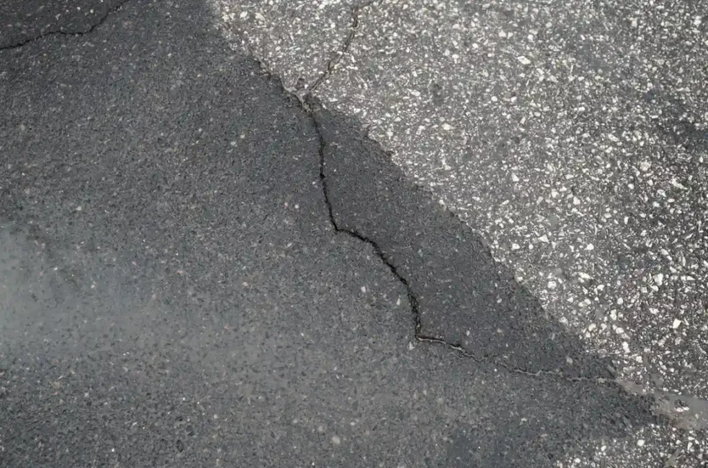 Damaged asphalt surface with visible cracks requiring asphalt repair and concrete repair as part of commercial property maintenance services