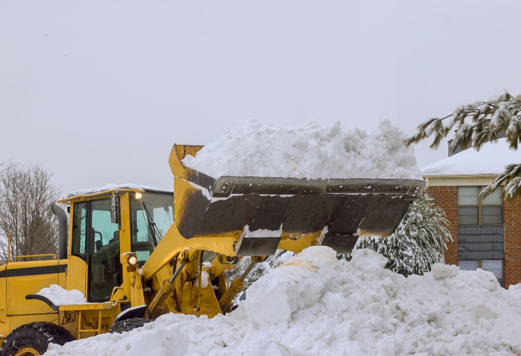 Heavy loader moving snow during parking lot snow removal as part of professional Parking Lot Maintenance services in winter.