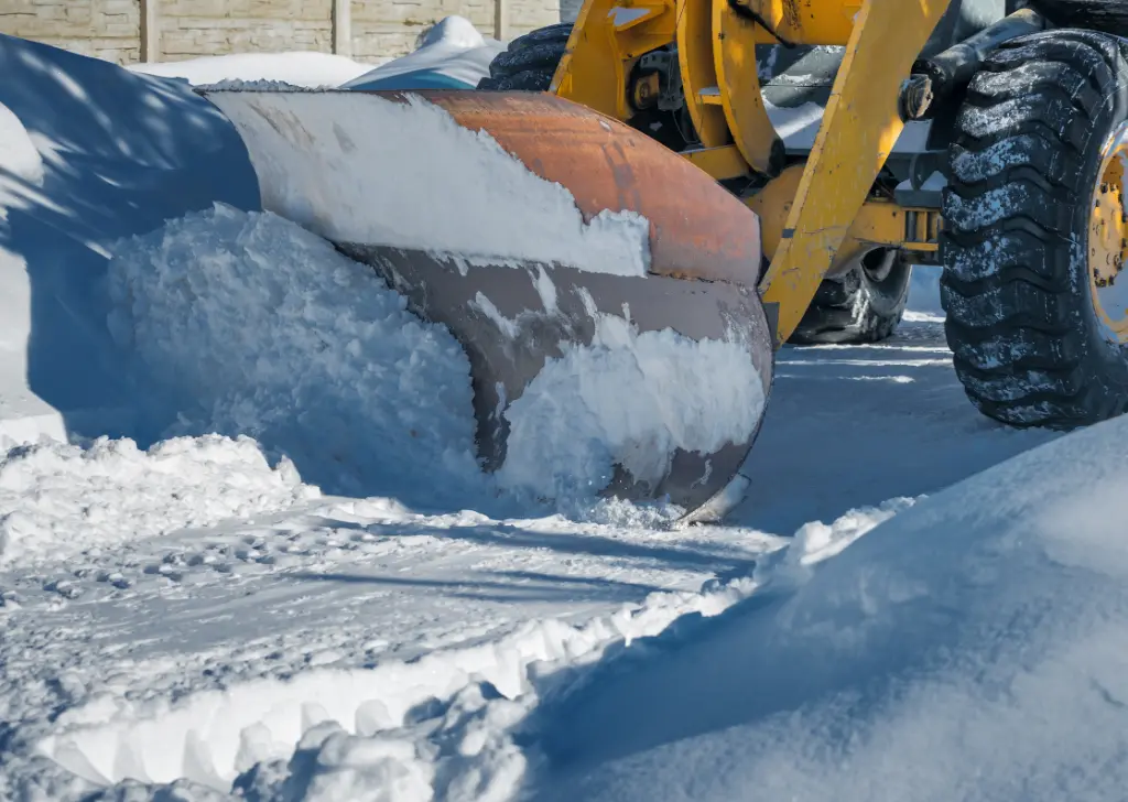 Heavy machinery performing parking lot snow removal as part of professional Parking Lot Maintenance during winter.