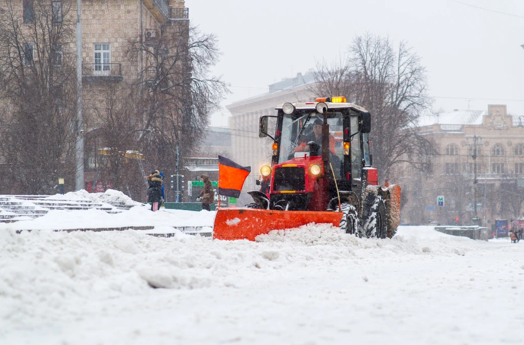 Urban snow removal with red tractor plowing streets during heavy snowfall 